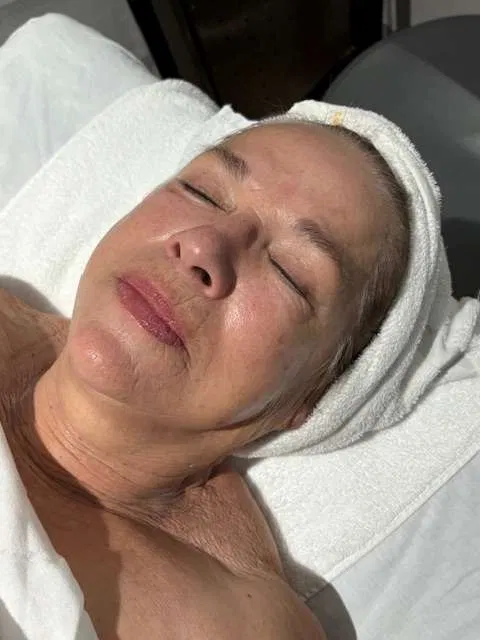 Client resting on the treatment bed with a warm towel turban